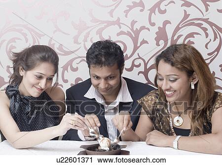 Two young women and a young man sharing dessert View Large Photo Image Stock Image - Two young women and a young man sharing dessert. Fotosearch