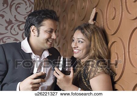 Stock Photo - Young couple holding glasses of red wine. Fotosearch