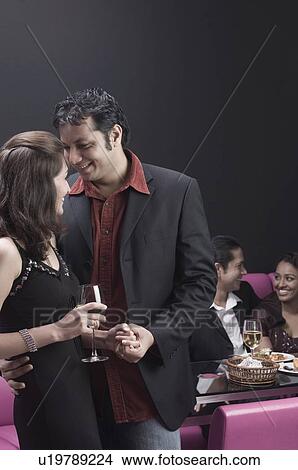 Picture - Young couple holding hands in a restaurant. Fotosearch