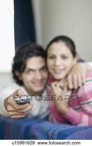 Young couple lying on a bed and watching television View Large Photo Image Stock Photo - Young couple lying on a bed and watching television. Fotosearch