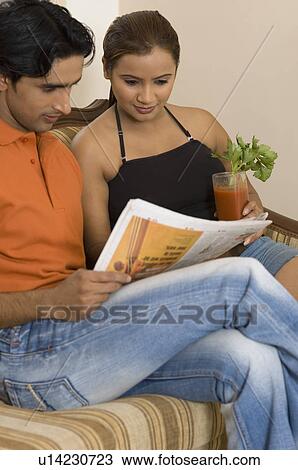 Young couple reading a newspaper View Large Photo Image Stock Image - Young couple reading a newspaper. Fotosearch