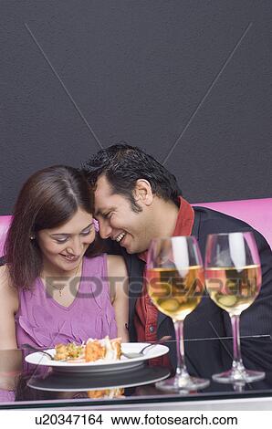 Picture - Young couple sitting in a restaurant and smiling. Fotosearch