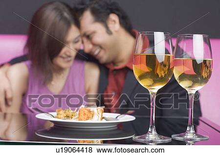Stock Photo - Young couple sitting with arm around in a restaurant. Fotosearch