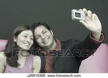 Stock Photograph - Young couple taking a photograph of themselves. Fotosearch