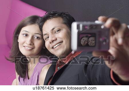 Stock Photography - Young couple taking a photograph of themselves. Fotosearch