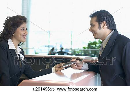 Young man giving a passport to an airline check-in attendant at a counter View Large Photo Image Stock Photography - Young man giving a passport to an airline check-in attendant at a counter. Fotosearch