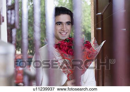 Stock Photo - Young man holding a bouquet of flowers and smiling. Fotosearch