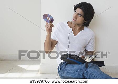 Stock Photograph - Young man listening to music and holding a CD. Fotosearch