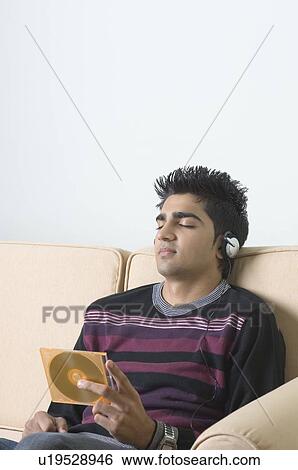 Young man listening to music and holding a CD case View Large Photo Image Stock Photograph - Young man listening to music and holding a CD case. Fotosearch