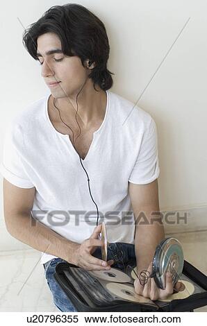 Young man listening to music View Large Photo Image Stock Photography - Young man listening to music. Fotosearch