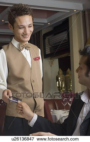 Stock Photo - Young man paying a bill with a credit card. Fotosearch