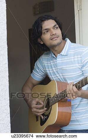 Picture - Young man playing a guitar. Fotosearch