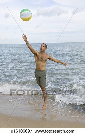 Young man playing with a beach ball on the beach View Large Photo Image Stock Photo - Young man playing with a beach ball on the beach. Fotosearch