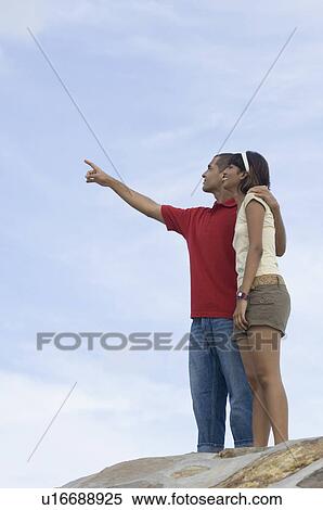 Stock Photography - Young man pointing forward with a mid adult woman beside him. Fotosearch
