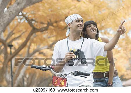 Stock Photo - Young man pointing with a mid adult woman sitting behind him. Fotosearch