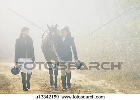 Young woman and a teenage girl walking with a horse View Large Photo Image Stock Photo - Young woman and a teenage girl walking with a horse. Fotosearch