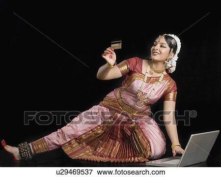 Young woman holding a credit card and using a laptop View Large Photo Image Stock Photo - Young woman holding a credit card and using a laptop. Fotosearch