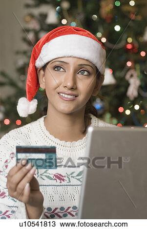 Young woman holding a credit card in front of a laptop View Large Photo Image Stock Image - Young woman holding a credit card in front of a laptop. Fotosearch