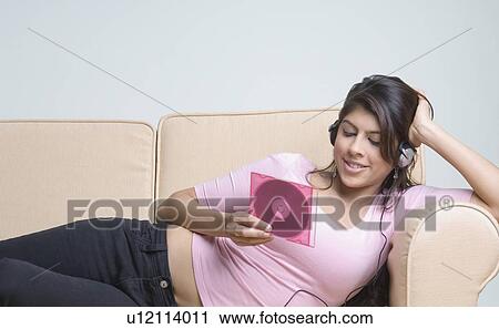 Stock Image - Young woman listening to music and holding a CD case. Fotosearch