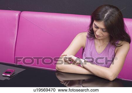 Young woman looking at her wristwatch View Large Photo Image Stock Image - Young woman looking at her wristwatch. Fotosearch