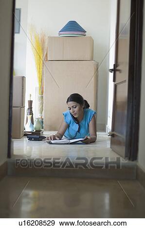 Stock Photo - Young woman lying on the floor and talking on the telephone. Fotosearch