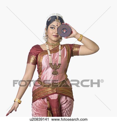 Stock Image - Young woman performing Bharatnatyam and holding a CD. Fotosearch