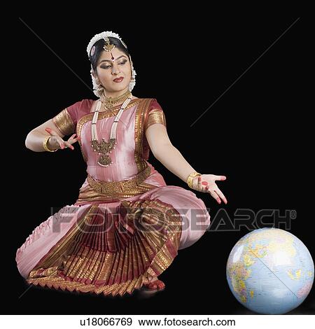 Stock Photo - Young woman performing Bharatnatyam and gesturing towards a globe. Fotosearch