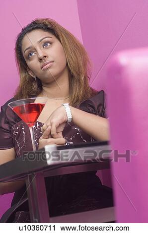 Stock Image - Young woman sitting in a restaurant and thinking. Fotosearch