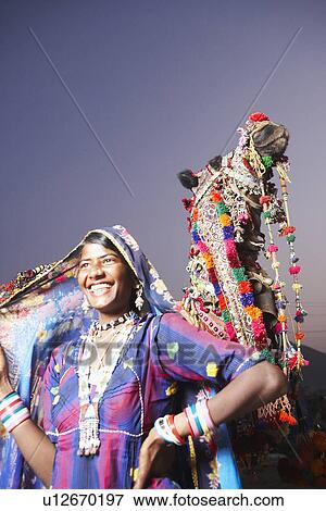 Stock Photo - Young woman standing with her hand on her hip and smiling. Fotosearch