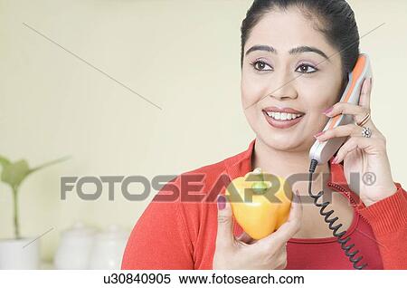 Young woman talking on the telephone and holding a yellow bell pepper View Large Photo Image Stock Photography - Young woman talking on the telephone and holding a yellow bell pepper. Fotosearch