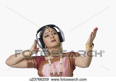 Stock Photo - Young woman wearing headphones and performing Bharatnatyam. Fotosearch