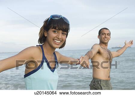 Portrait of a young couple holding hands on the beach and smiling View Large Photo Image Picture - Portrait of a young couple holding hands on the beach and smiling. Fotosearch