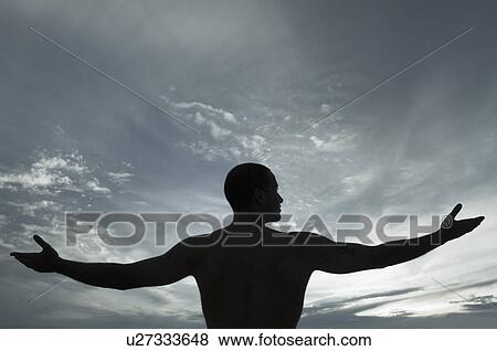 Stock Photo - Silhouette of a man standing with his arms outstretched. Fotosearch