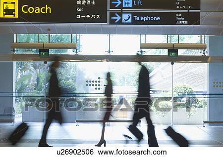 Stock Photograph - Silhouette of three business executives pulling luggage at an airport. Fotosearch