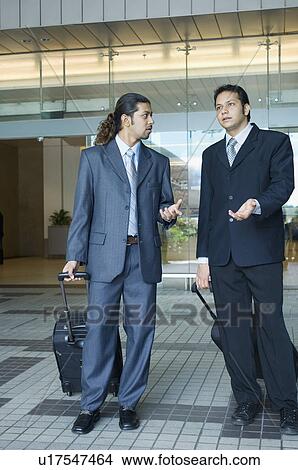 Two businessmen having a discussion at an airport View Large Photo Image Picture - Two businessmen having a discussion at an airport. Fotosearch