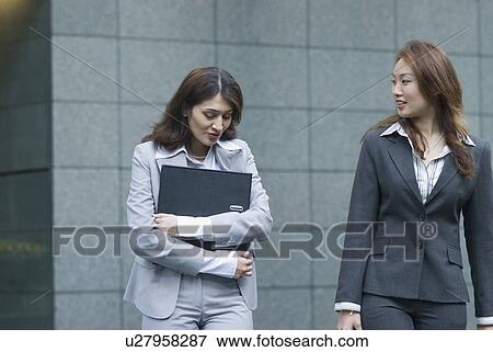 Two businesswomen talking to each other View Large Photo Image Stock Photo - Two businesswomen talking to each other. Fotosearch
