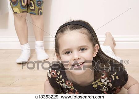 Girl on floor girl standing behind View Large Photo Image Stock Photo - Girl on floor girl standing behind. Fotosearch