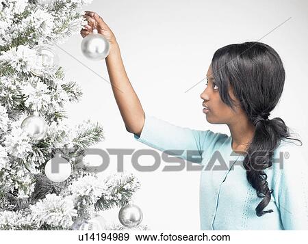 Stock Photo - Woman hanging Christmas decoration. Fotosearch
