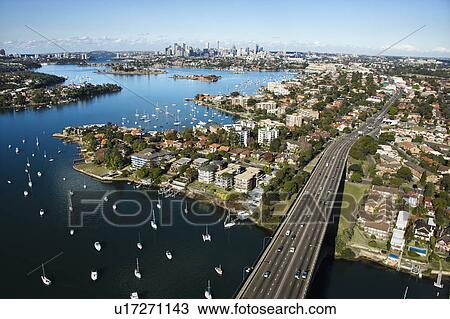 Stock Image - Aerial view of Victoria Road bridge and boats with distant downtown skyline in Sydney, Australia. Fotosearch