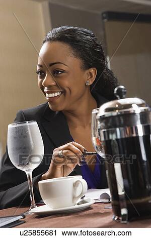 Stock Image - African American businesswoman smiling and sitting at table in restaurant.. Fotosearch