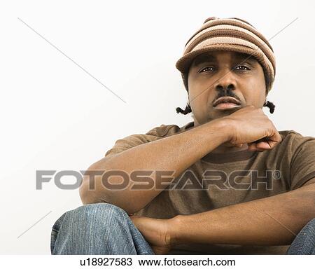 Stock Image - African-American mid-adult man wearing hat looking at viewer.. Fotosearch