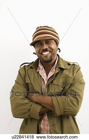 Stock Photo - African-American mid-adult man wearing hat and smiling at viewer with arms crossed.. Fotosearch