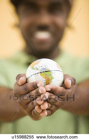African-American mid-adult man wearing hat holding small globe toviewer. View Large Photo Image Stock Photography - African-American mid-adult man wearing hat holding small globe toviewer.. Fotosearch