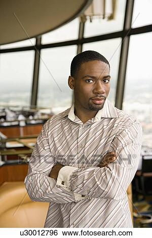 Stock Photograph - African American mid adult man with arms crossed looking at viewer.. Fotosearch