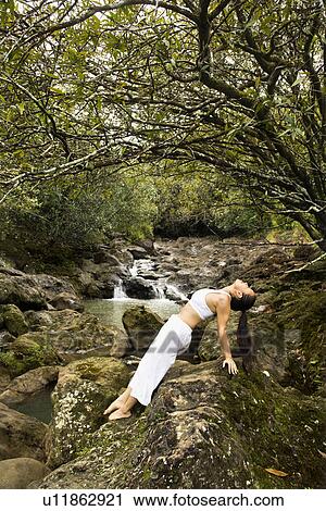 Asian American woman doing yoga balancing on boulder by creek in Maui, Hawaii. View Large Photo Image Stock Image - Asian American woman doing yoga balancing on boulder by creek in Maui, Hawaii.. Fotosearch