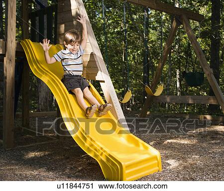 Boy sliding down outdoor slide with arms raised above head View Large Photo Image Stock Image - Boy sliding down outdoor slide with arms raised above head. Fotosearch