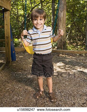 Stock Photo - Boy standing by swing set. Fotosearch