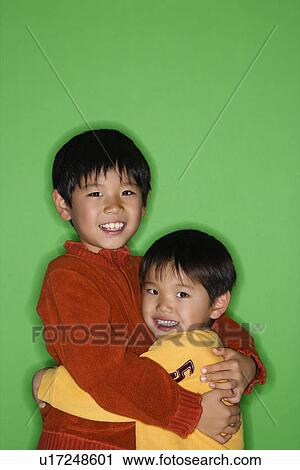 Stock Image - Brothers hugging each other smiling. Fotosearch