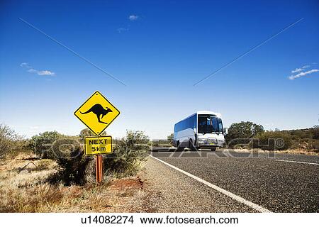 Picture - Bus on two lane asphalt road in rural Australia with kangaroo crossing sign.. Fotosearch