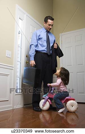 Businessman at door with briefcase with daughter looking up at him View Large Photo Image Stock Photo - Businessman at door with briefcase with daughter looking up at him. Fotosearch